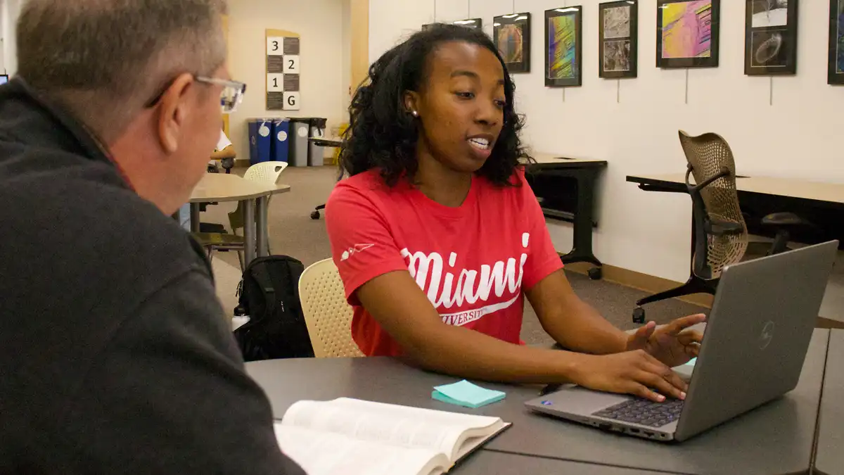 Student using a laptop with a librarian
